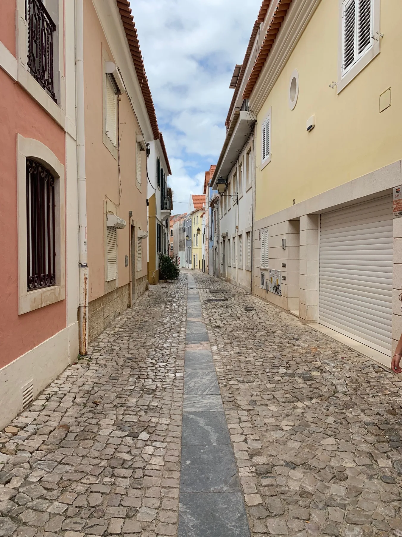 Una calle estrecha empedrada transcurre entre edificios de tonos pastel.