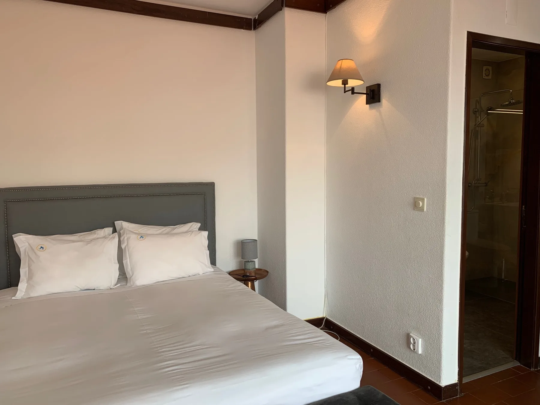 Un dormitorio con la cama tendida y una lámpara de pared.