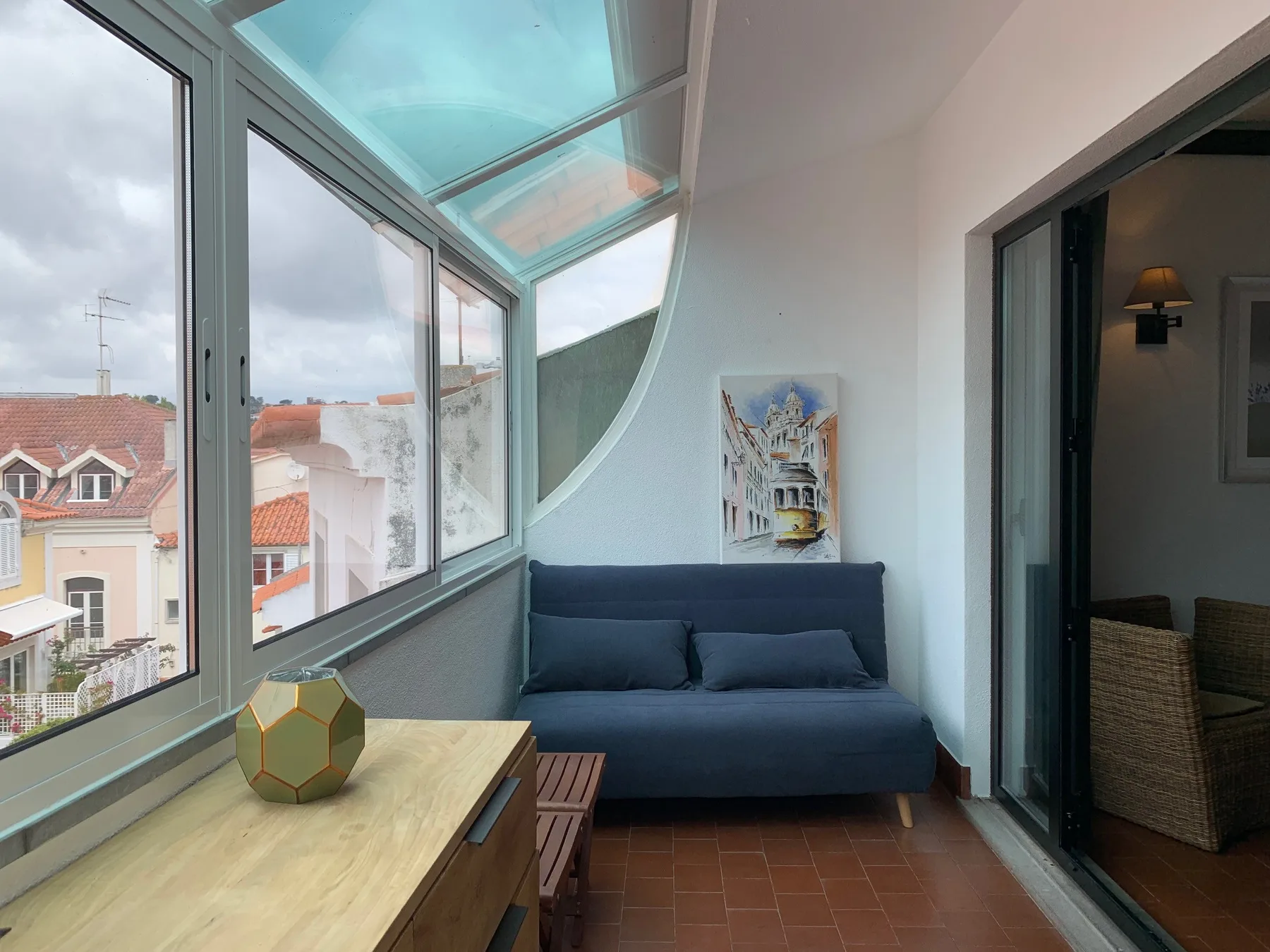 Una zona de estar luminosa con un sofá azul junto a grandes ventanas.