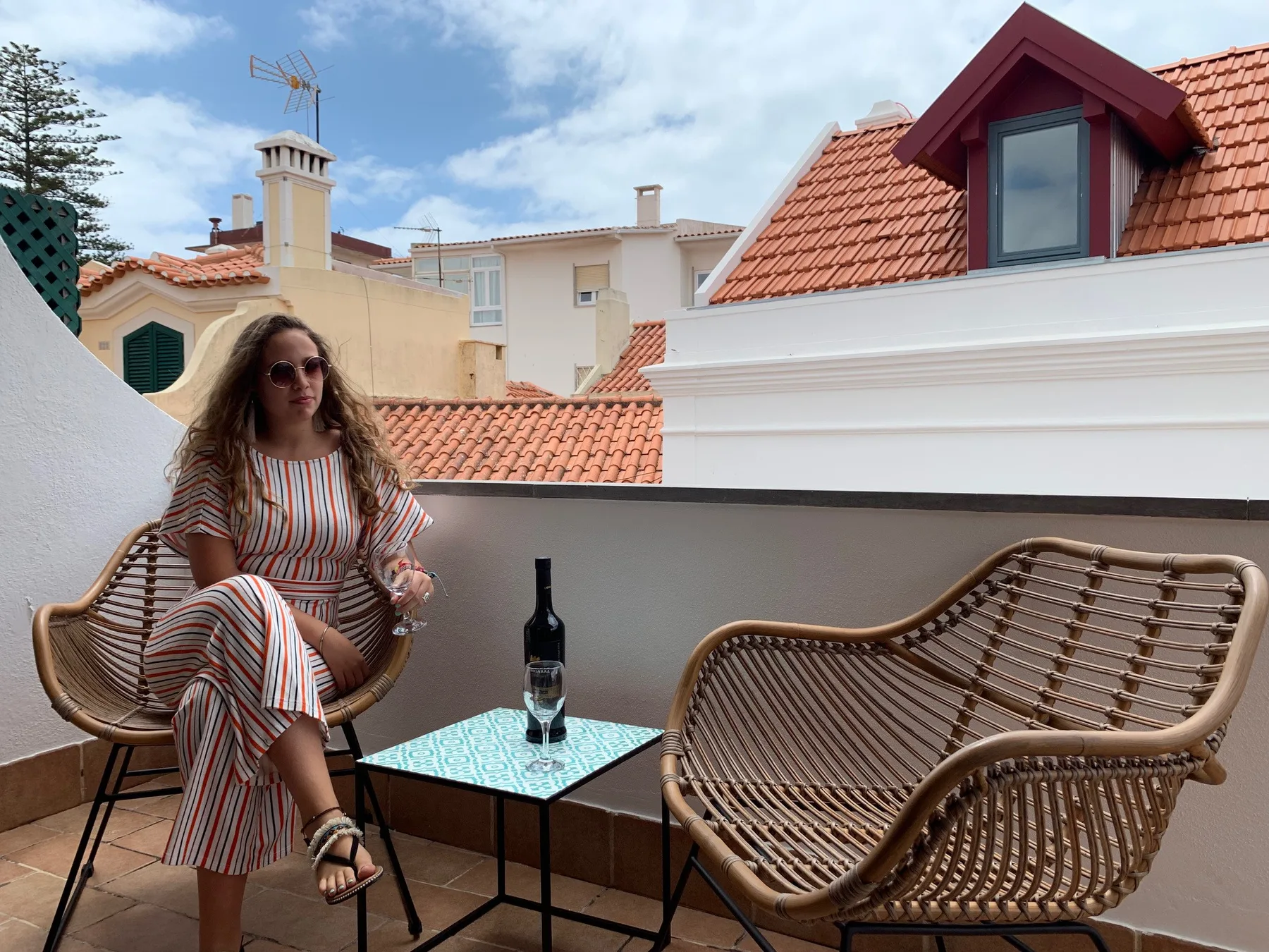 Una terraza en la azotea con asientos tejidos y vistas a tejados cercanos.