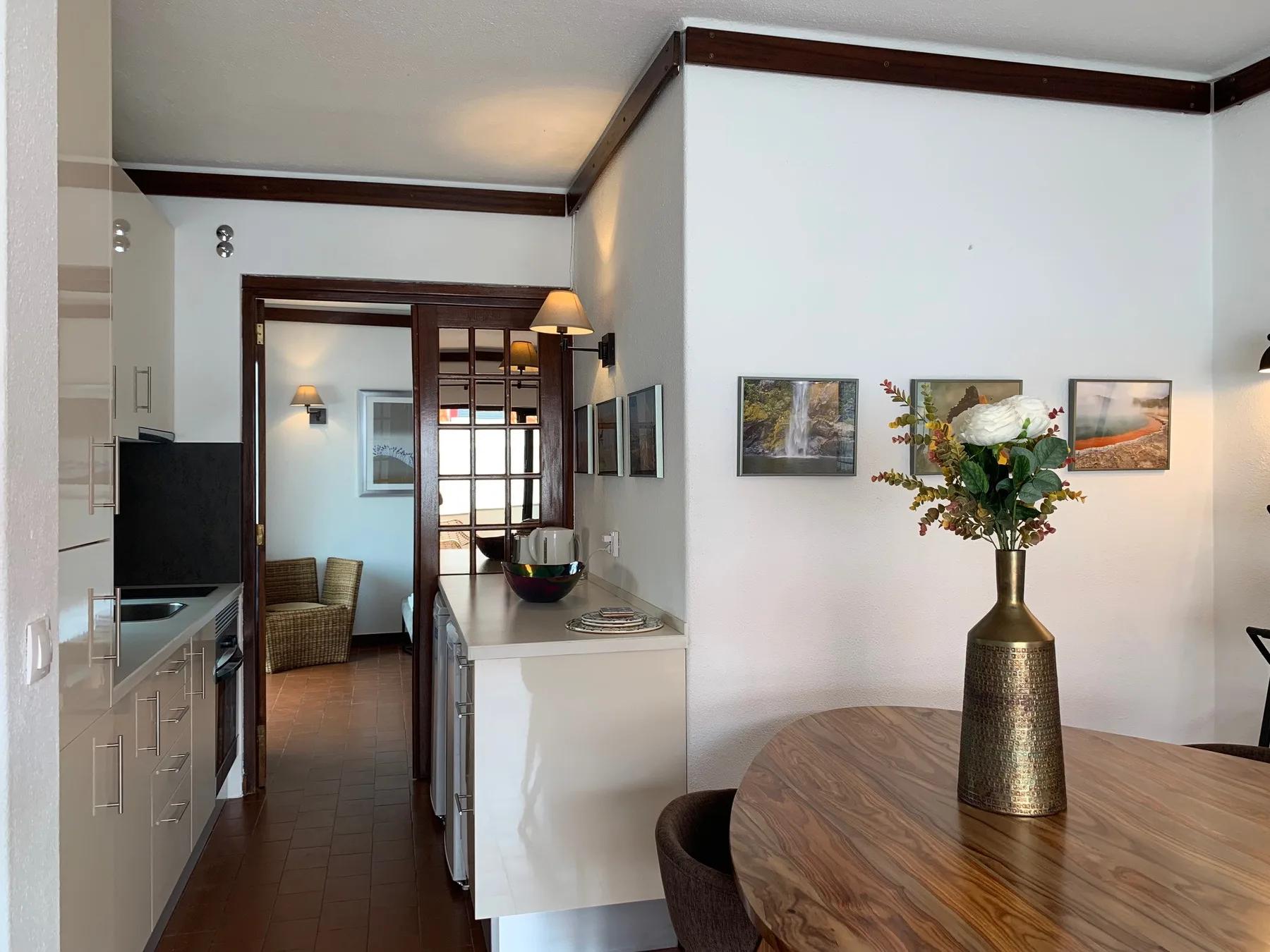 Comedor con una mesa de madera y un jarrón de flores junto a la cocina.
