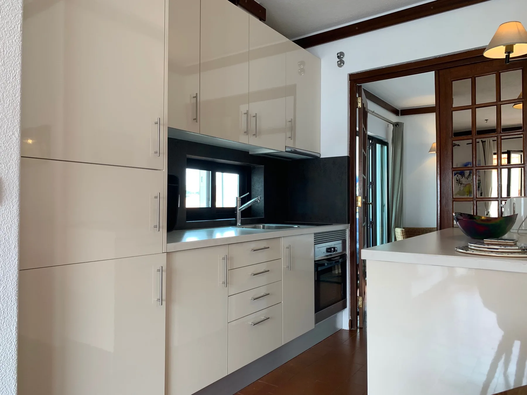 Una cocina luminosa con gabinetes blancos, encimeras oscuras y un horno integrado.