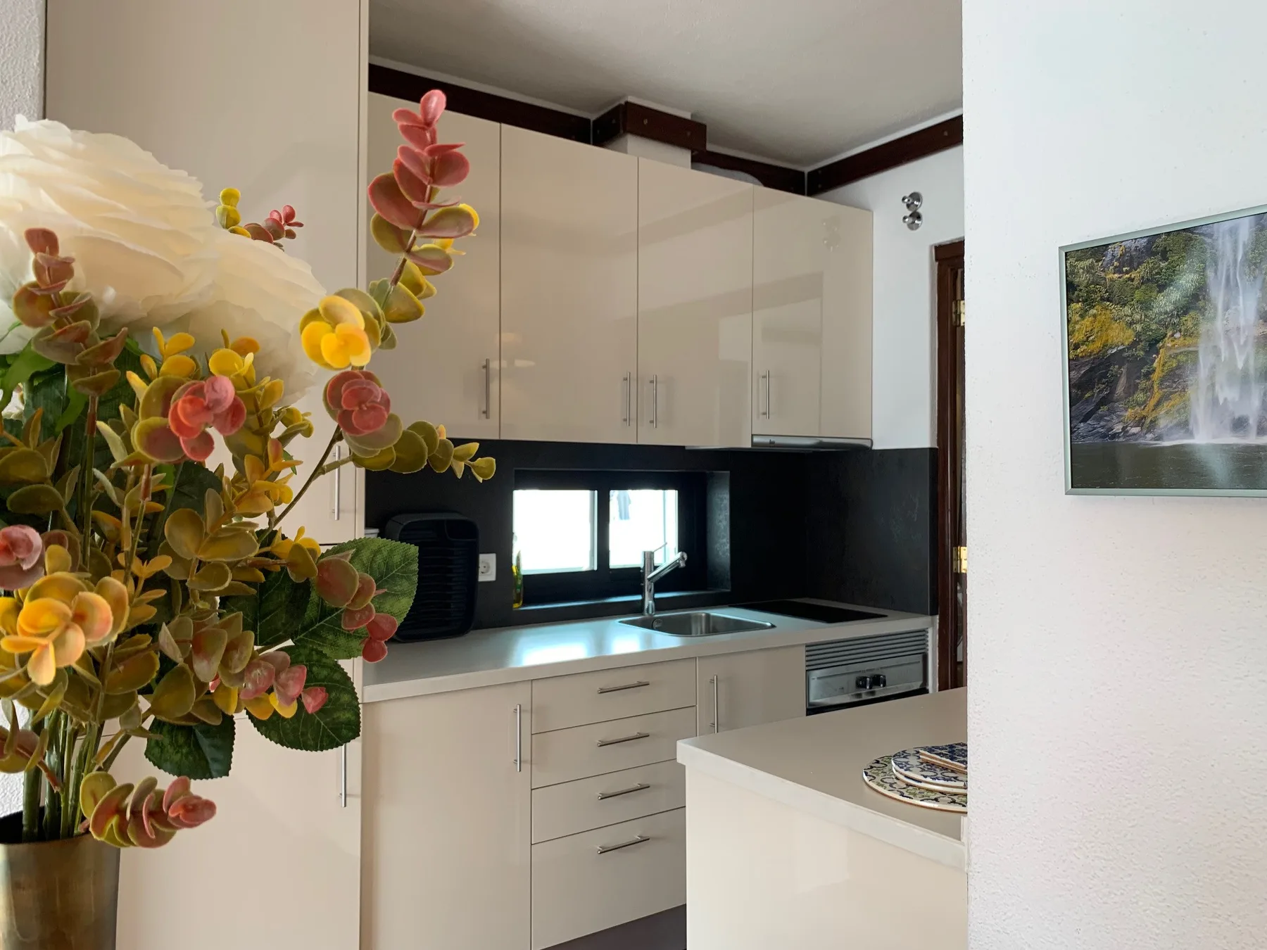 Una cocina luminosa con armarios claros, una encimera oscura y un fregadero.