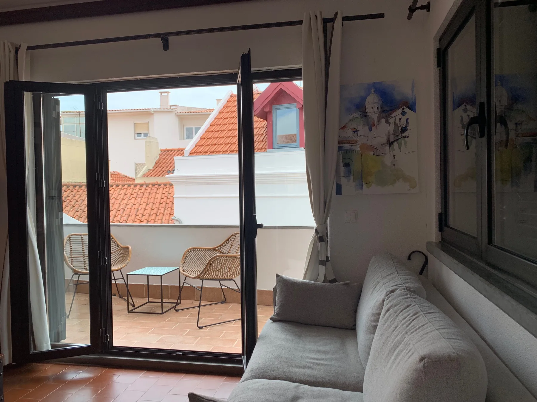 Una sala de estar con asientos da a un balcón a través de puertas de vidrio.