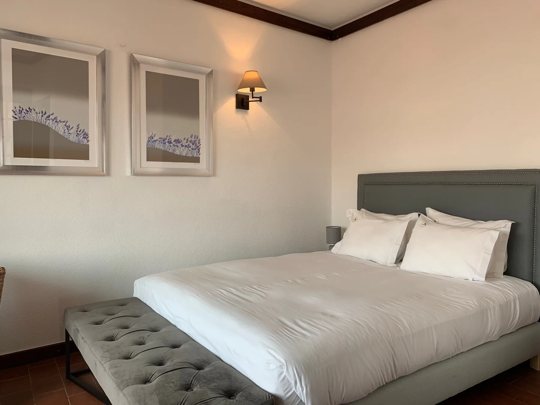 Un dormitorio con una cama bien hecha y un banco acolchado.