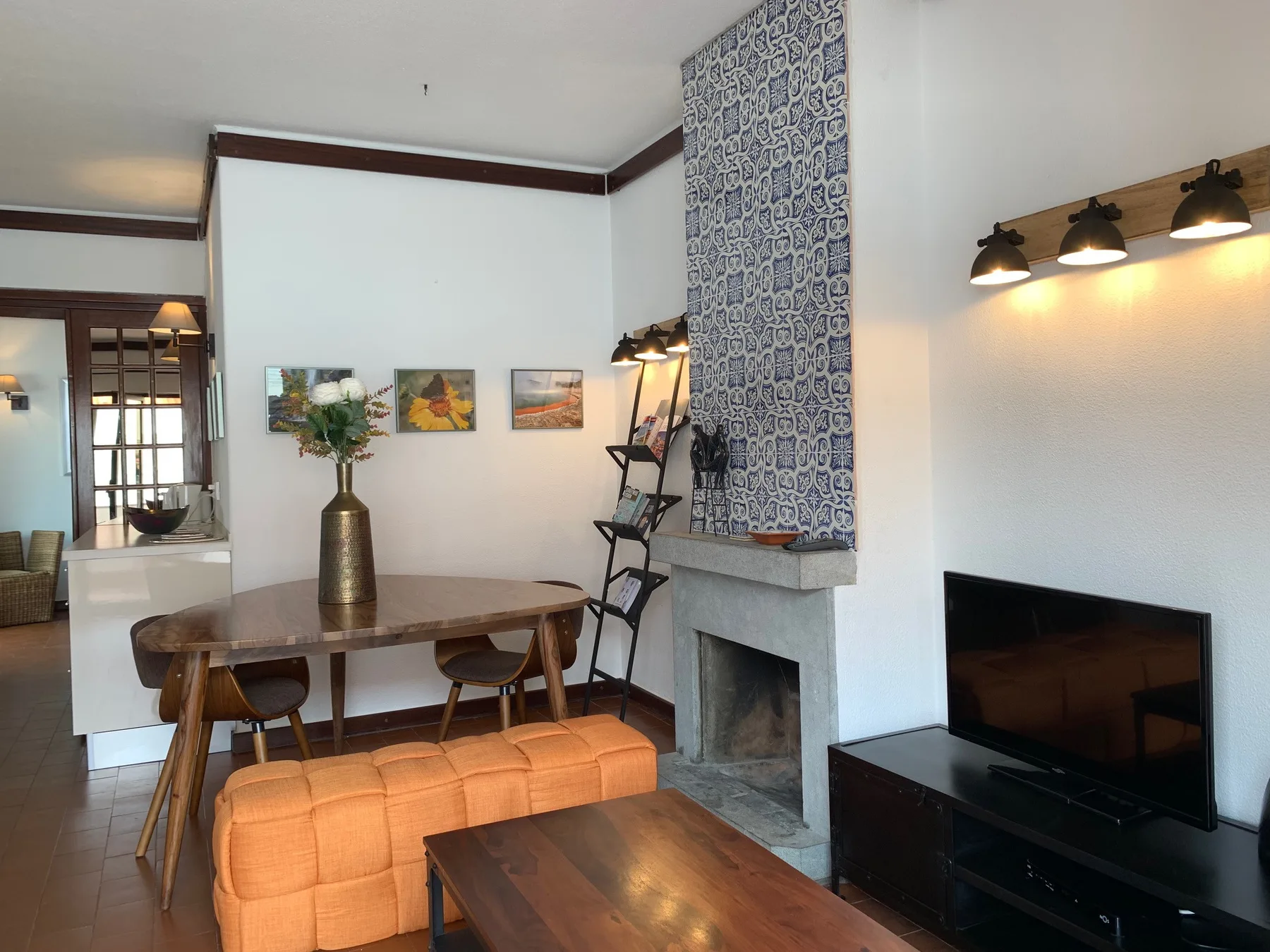 Una sala de estar con mesa de comedor, televisor y chimenea revestida de azulejos.