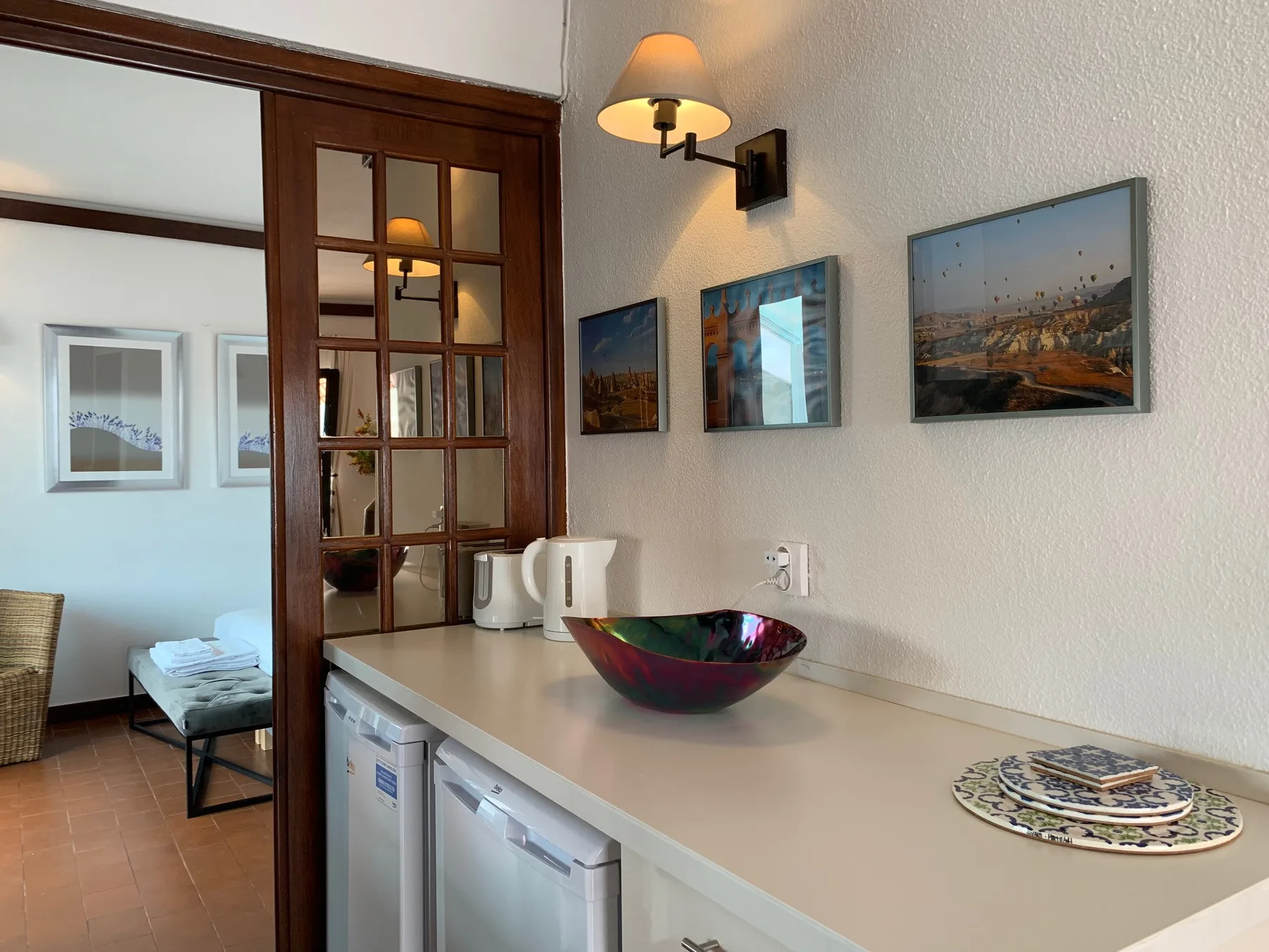 Una encimera de cocina con fregadero y cuadros junto a una zona de estar.