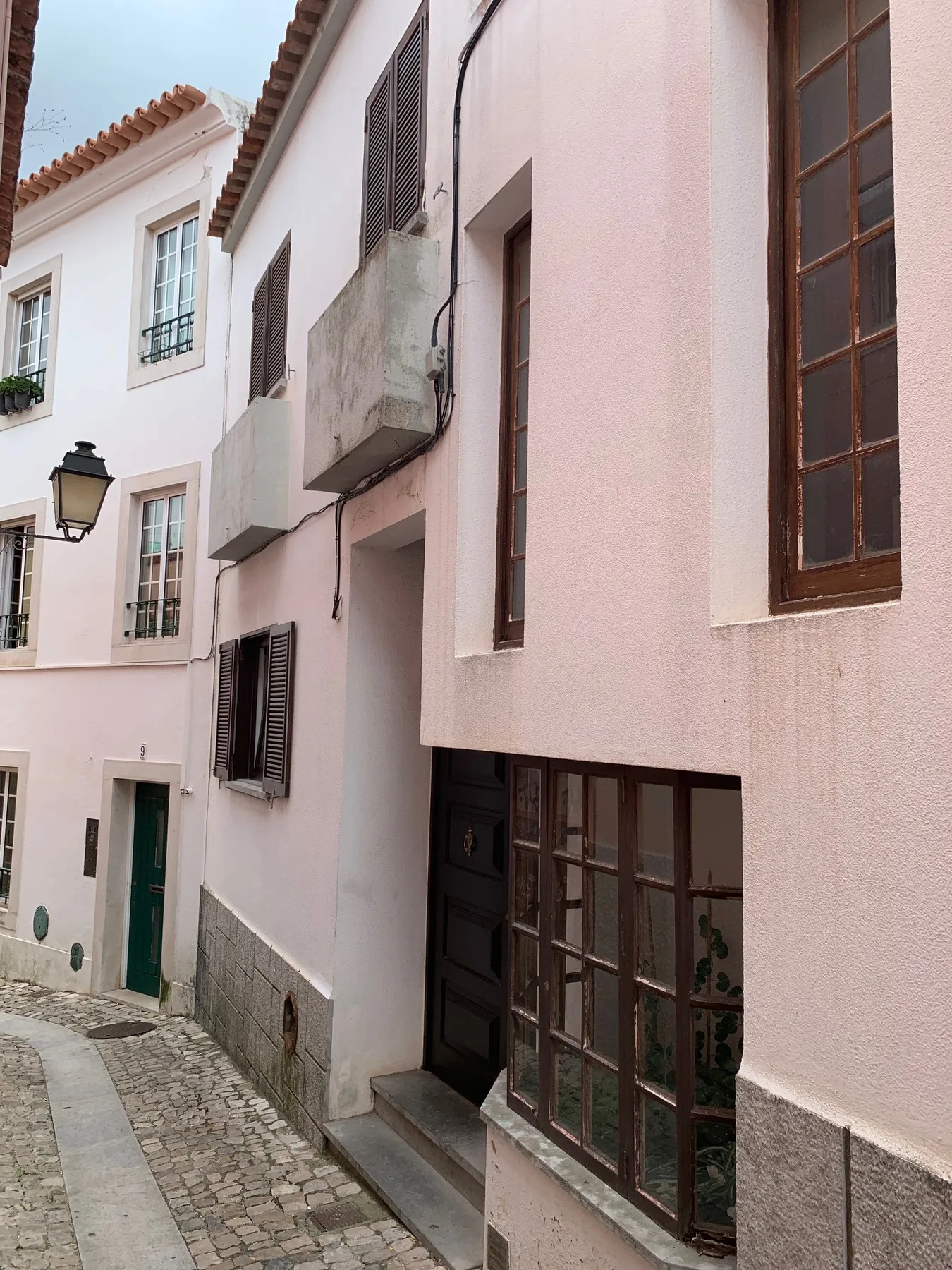 Una calle estrecha de adoquines pasa entre edificios de tonos pastel con ventanas altas.