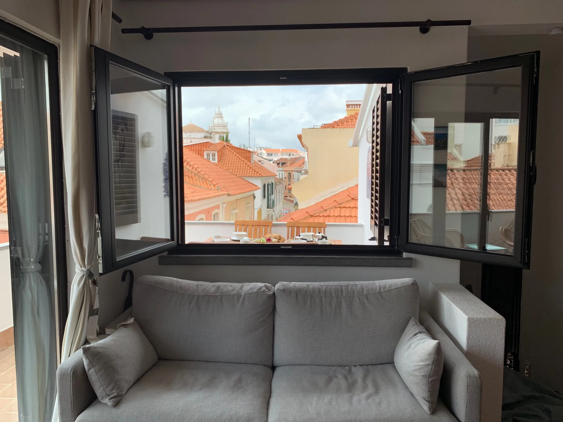Una zona de estar junto a una ventana abierta da a los tejados cercanos.