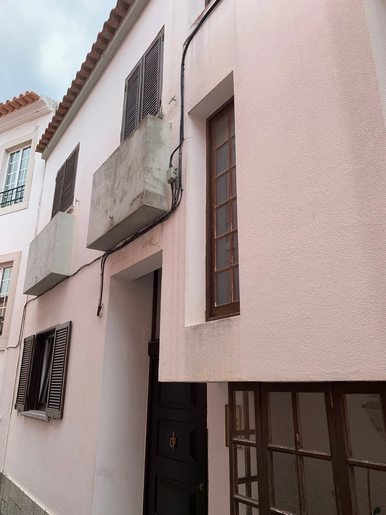 Una fachada rosa pálido tiene ventanas de marco oscuro y una puerta de entrada negra.