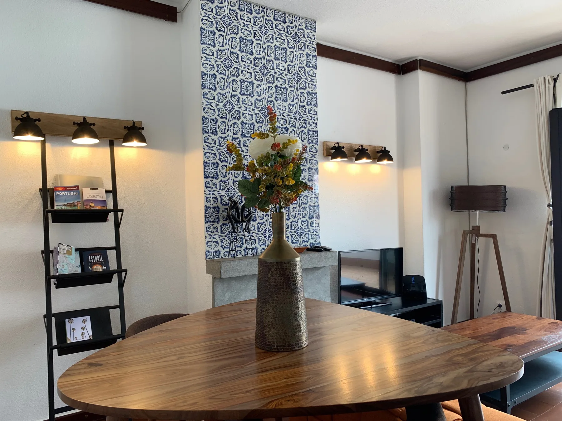Una sala de estar con una mesa grande de madera y azulejos estampados en la pared.