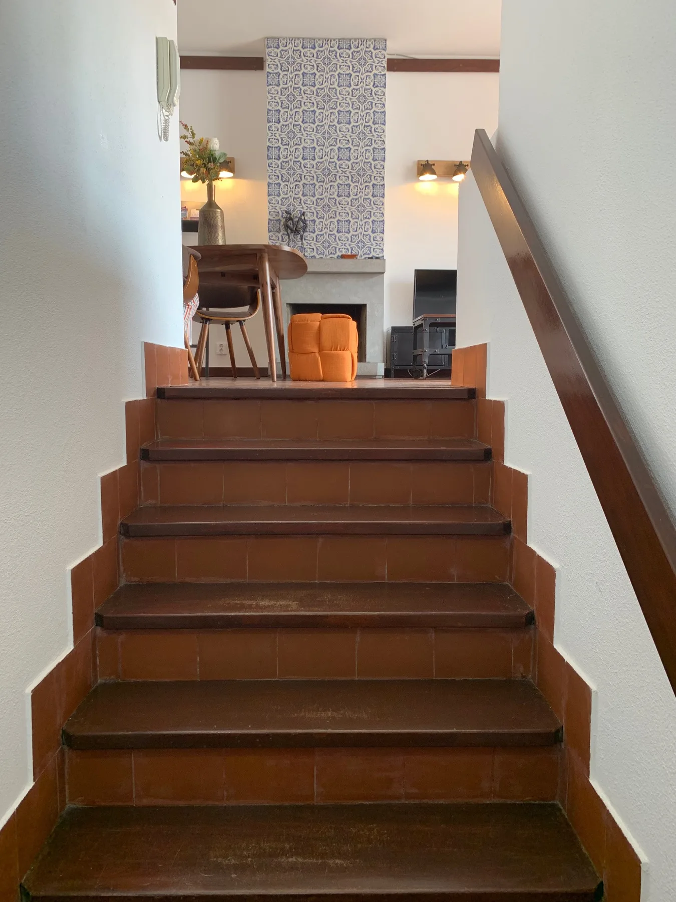 Una escalera de baldosas conduce a una pequeña sala de estar con asientos y una mesa de comedor.