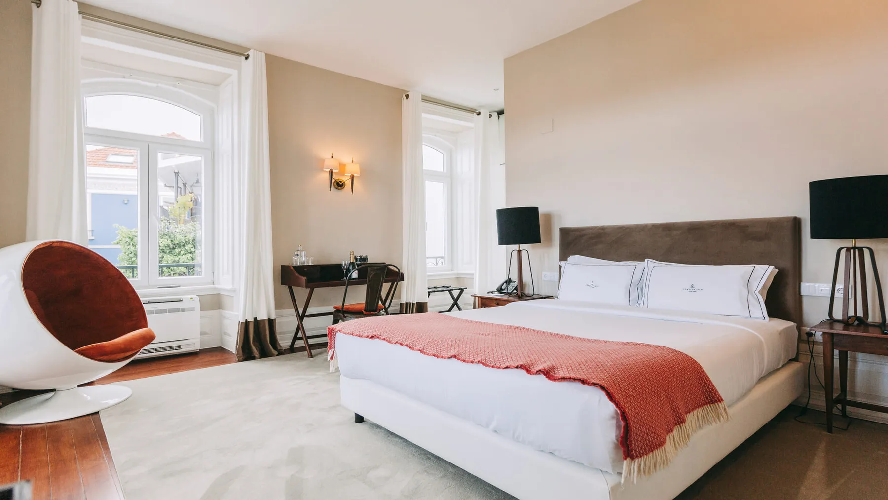 Dormitorio con una cama, una silla y ventanas con cortinas
