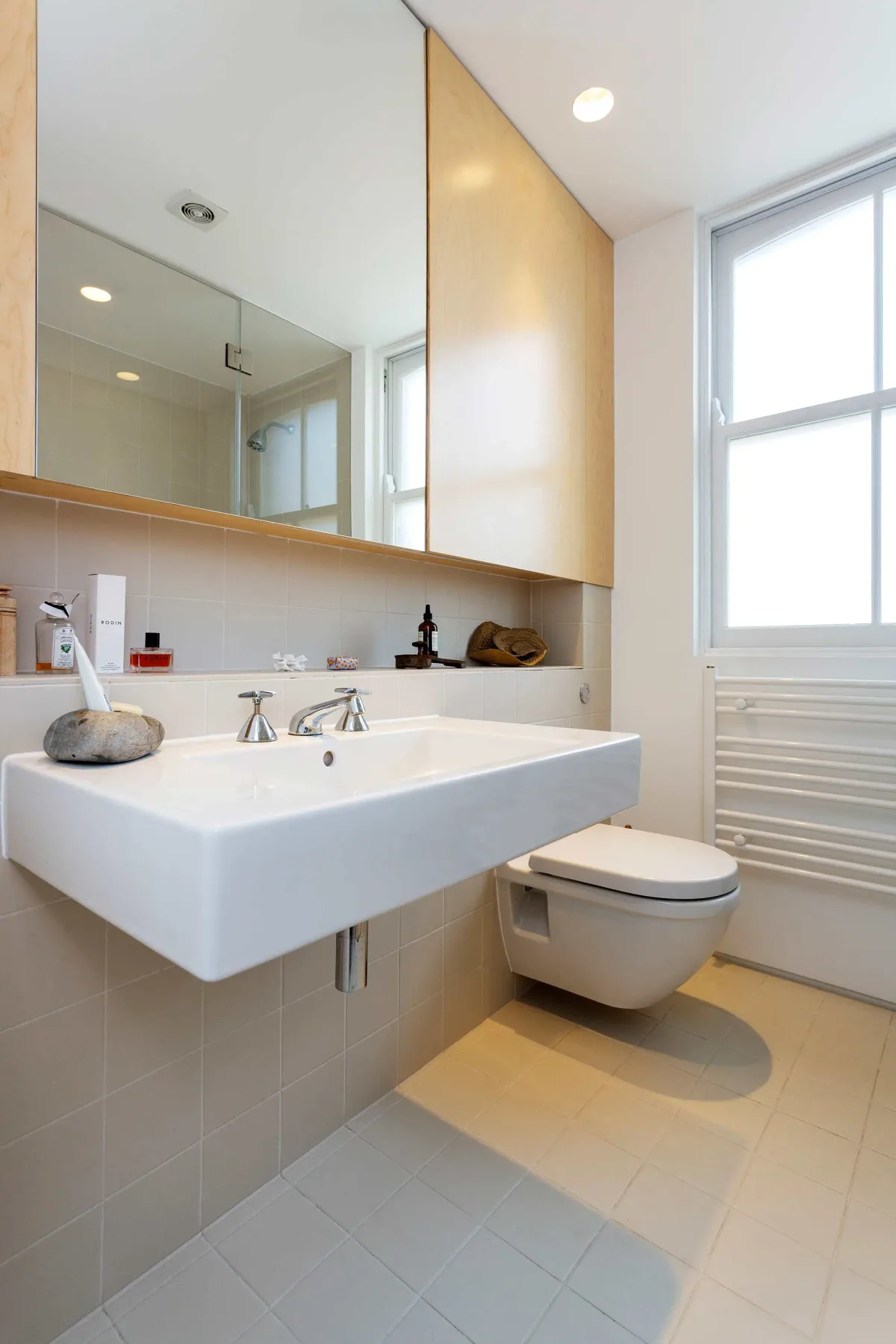 Un baño luminoso con lavabo suspendido y un espejo grande.