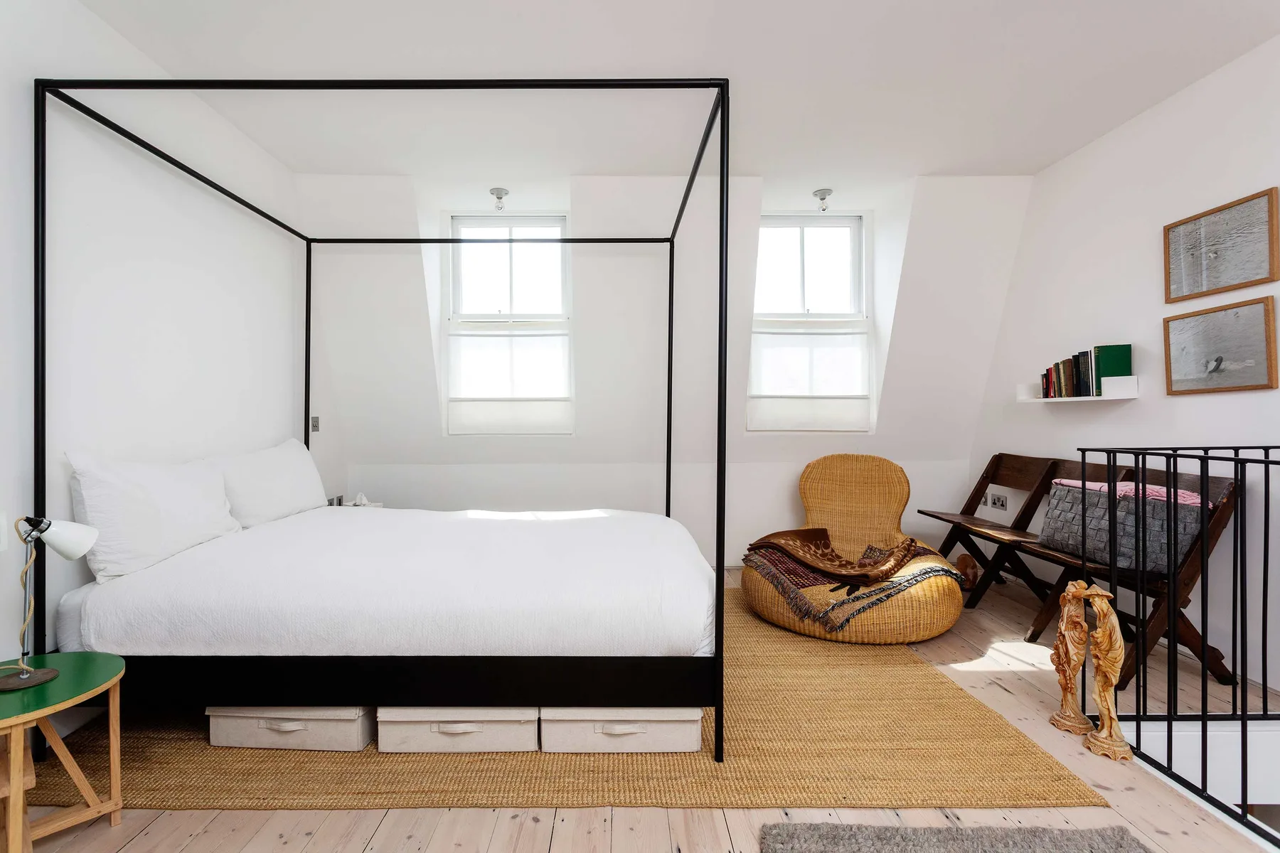 Dormitorio luminoso con cama con dosel, alfombra tejida y zona de estar.
