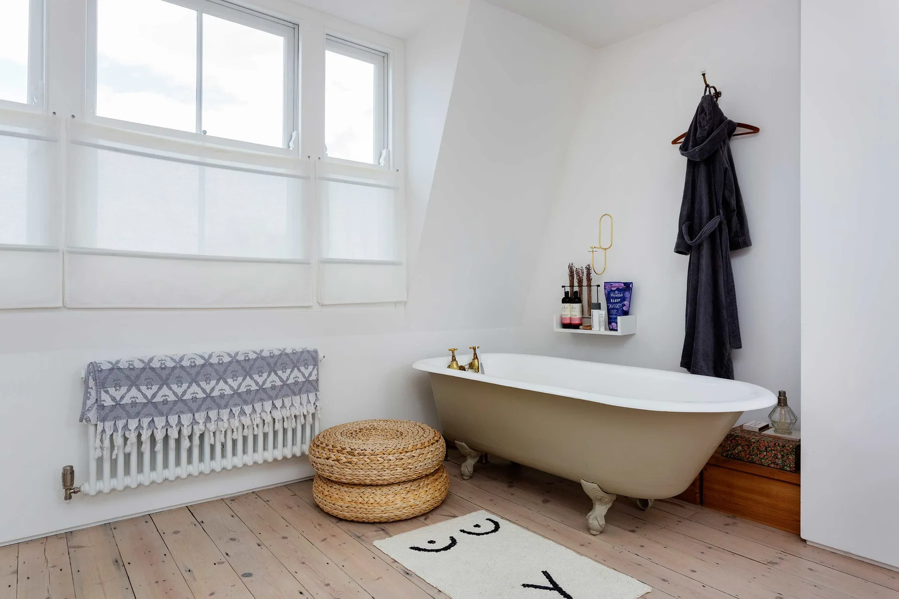 Un baño luminoso con una bañera exenta bajo una gran ventana.