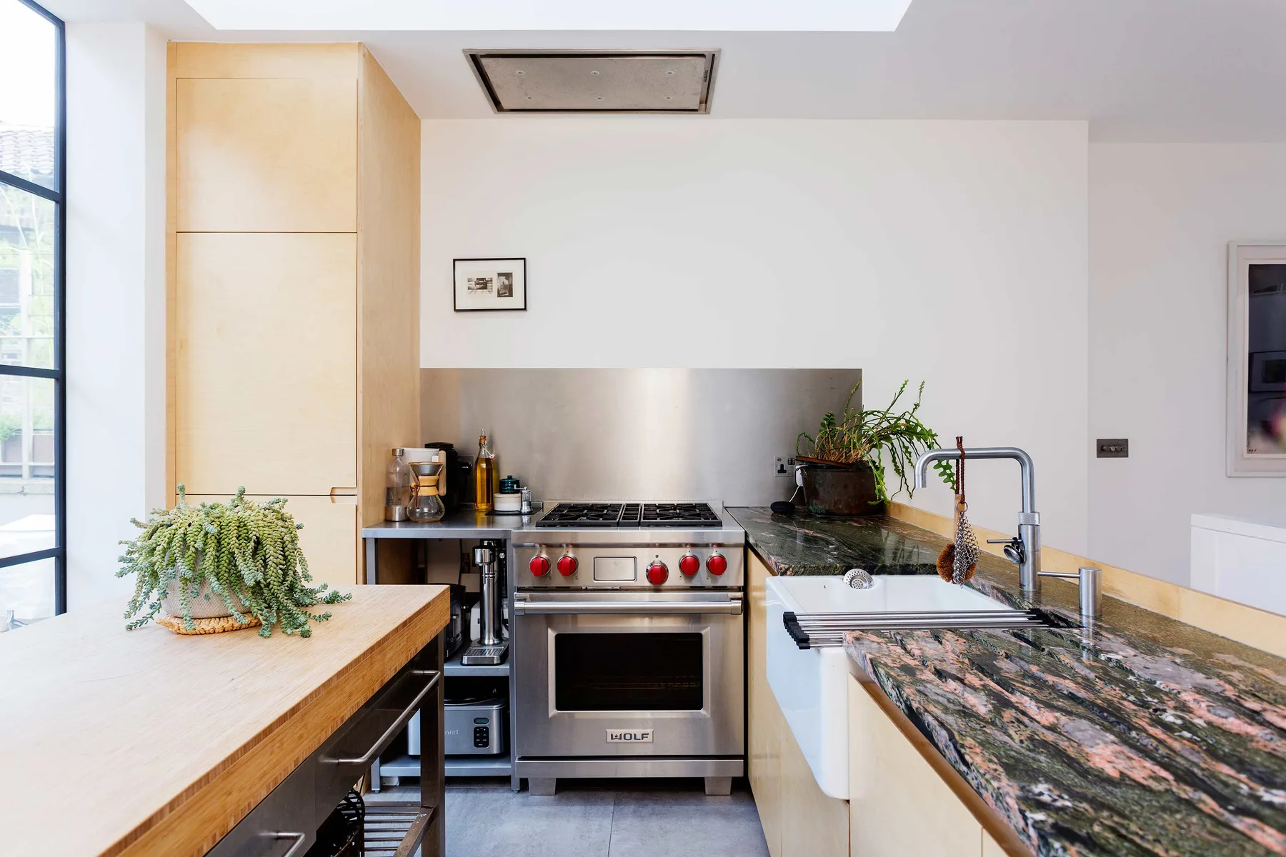 Una cocina luminosa con una estufa de acero inoxidable y una larga encimera de piedra.