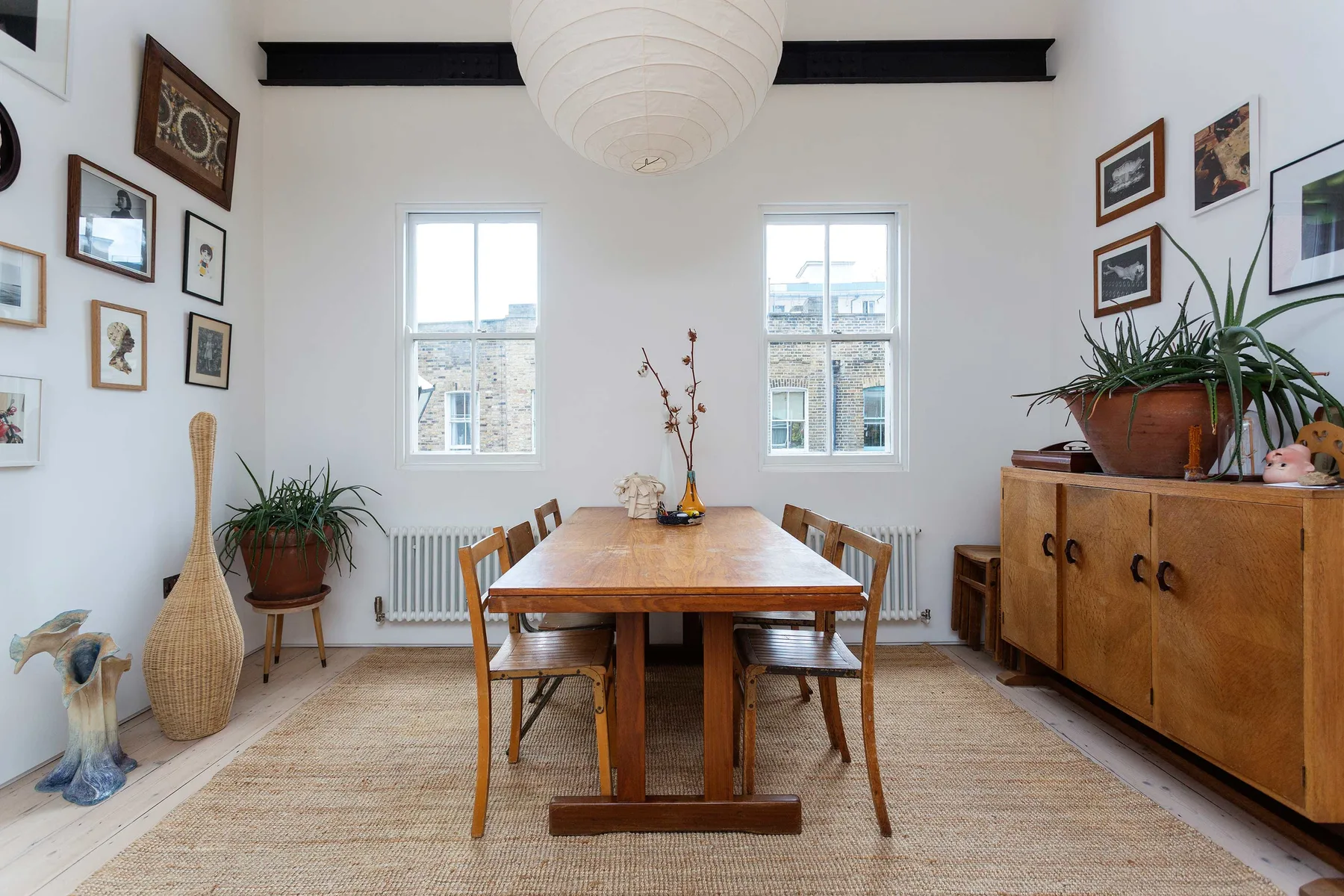Un comedor luminoso con una mesa de madera, asientos y cuadros en las paredes.
