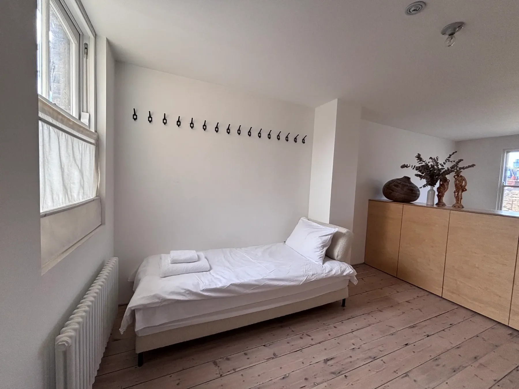 Un dormitorio sencillo con una cama baja y un mueble de madera.
