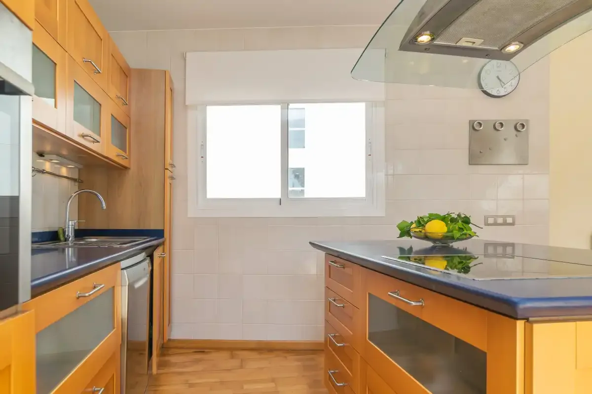 Una cocina luminosa con gabinetes de madera, una isla central y una ventana.