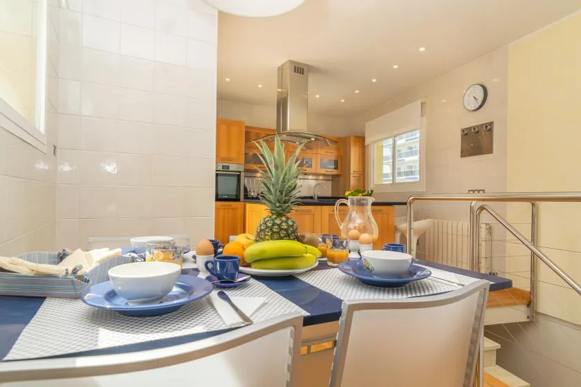 Una luminosa cocina con comedor y una mesa puesta junto a la encimera.