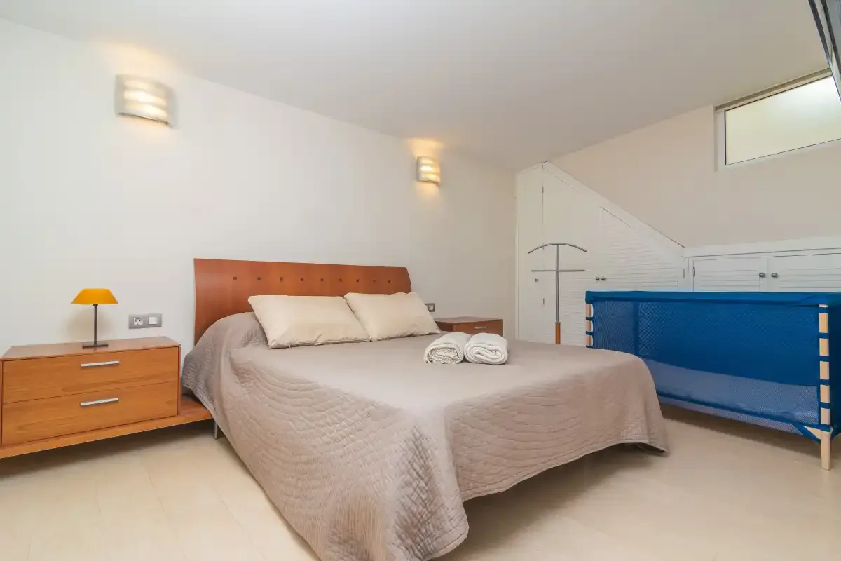 Un dormitorio con una cama doble, una mesita de noche y un mueble azul.
