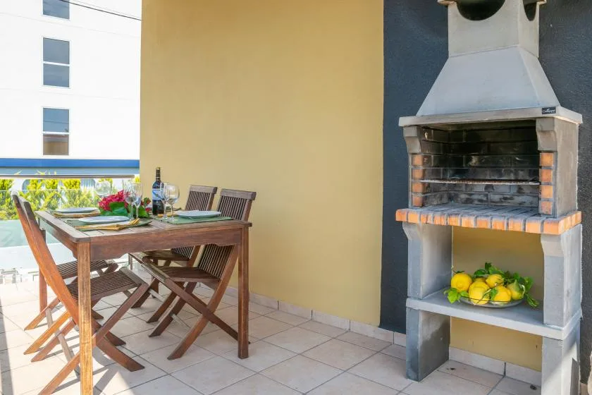 Una zona de comedor al aire libre con una mesa de madera junto a una barbacoa.