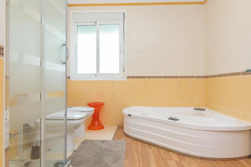 Un baño con bañera, ducha y ventana.