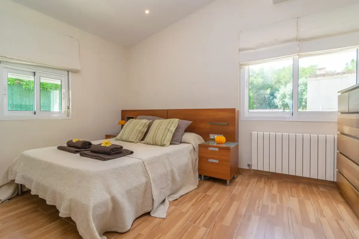 Un dormitorio con una cama doble y ventanas con vistas a zonas verdes.