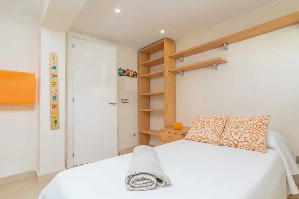 Un dormitorio con una cama bien arreglada y estantes de madera.