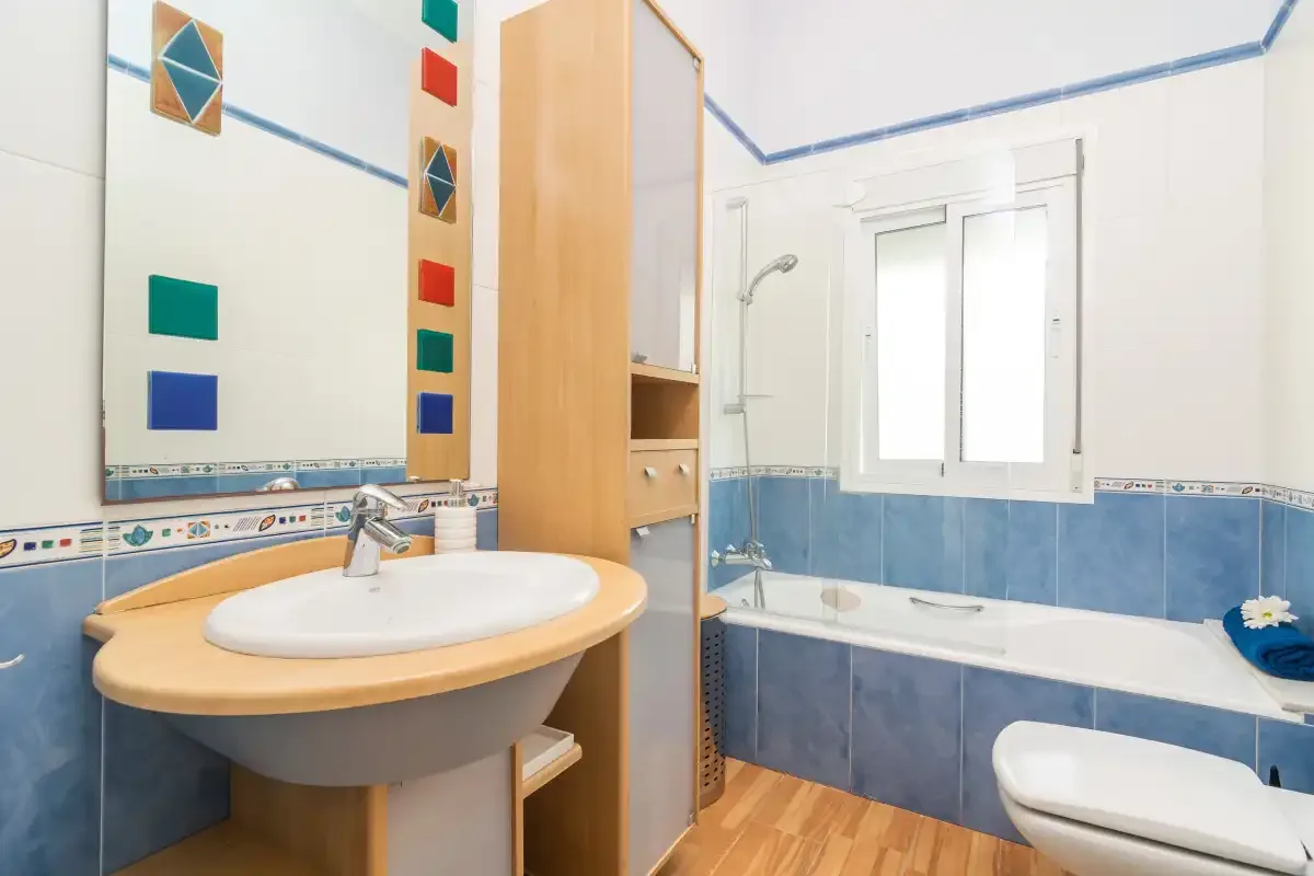 Un baño luminoso con lavabo, bañera y ventana.