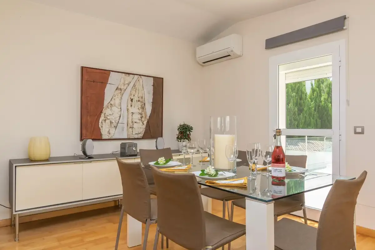 Comedor con una mesa de cristal, asientos marrones y una ventana amplia.