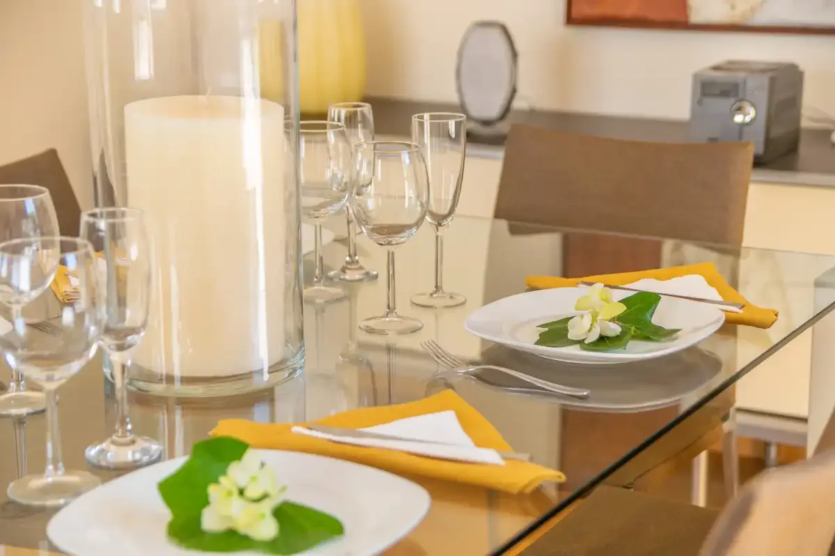 Una mesa está preparada con platos, servilletas dobladas y copas de vino.