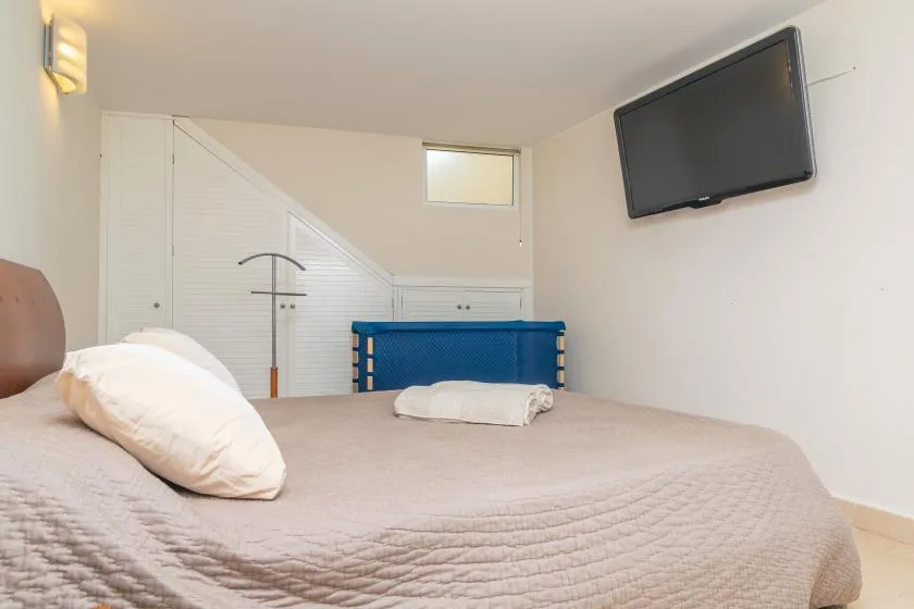 Un dormitorio con una cama y un televisor montado en la pared.