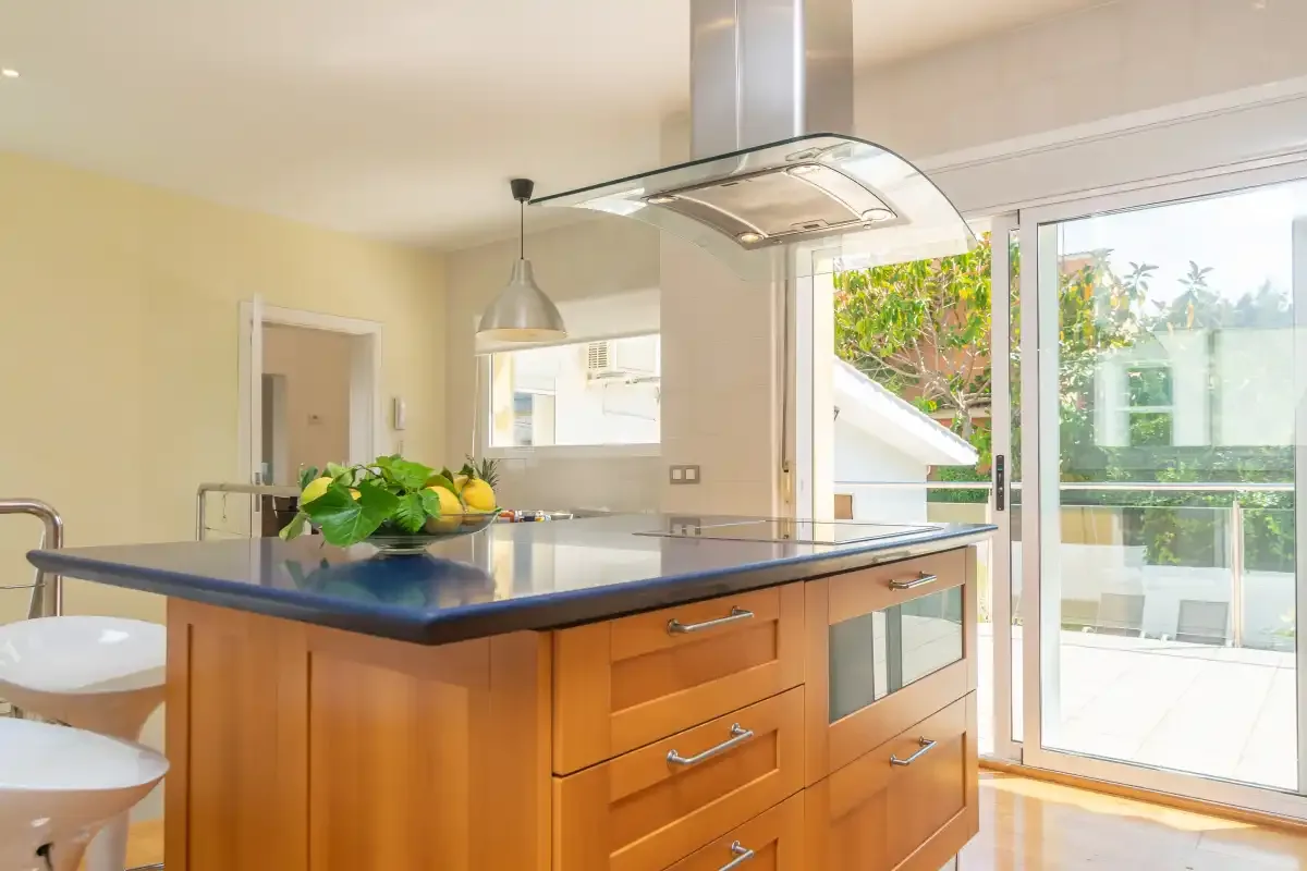 Una cocina luminosa con una isla central y puertas de vidrio hacia un patio.