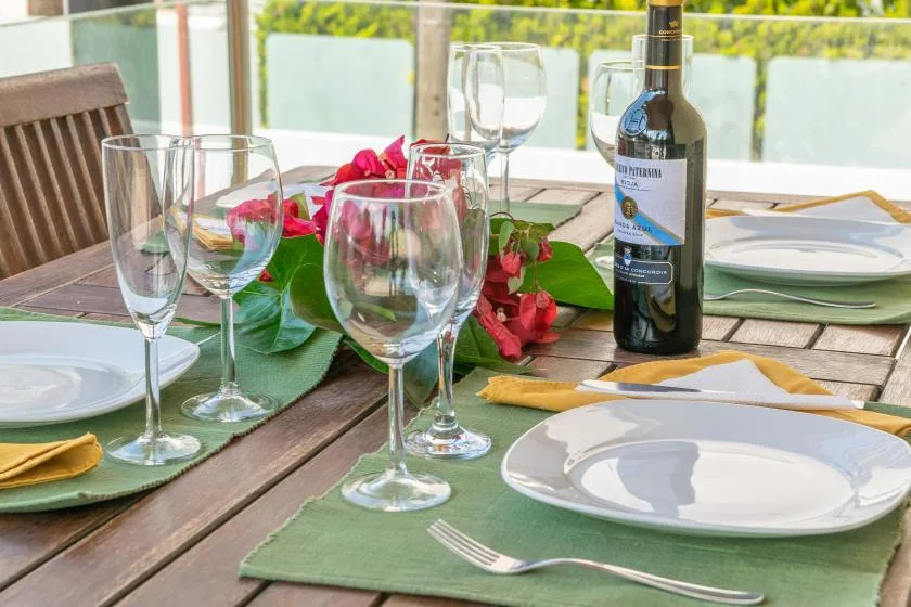 Una mesa de comedor está puesta con platos, copas de vino y una botella de vino.