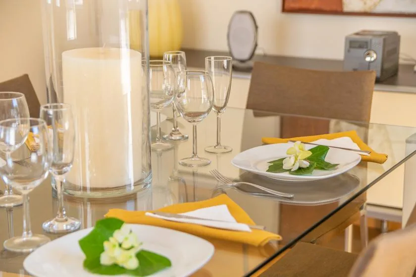 Una mesa de comedor está puesta con platos, servilletas dobladas y cristalería.