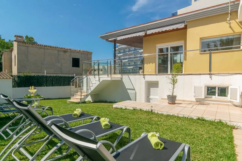 Un patio soleado con asientos de descanso junto a un edificio amarillo.