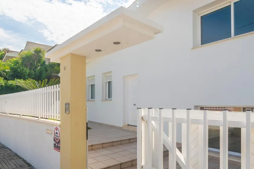 Entrada luminosa de una casa moderna, con pasillo de baldosas y puerta blanca.