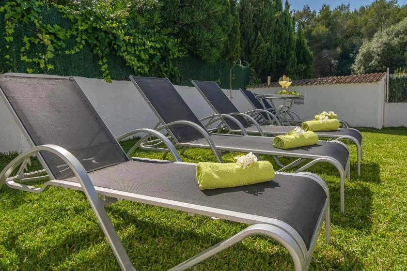 Outdoor lounge area with reclining loungers and folded towels on the grass.