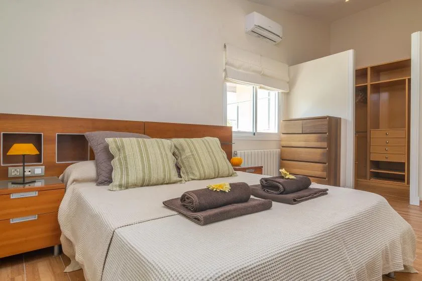 Un dormitorio con una cama bien arreglada y toallas dobladas.