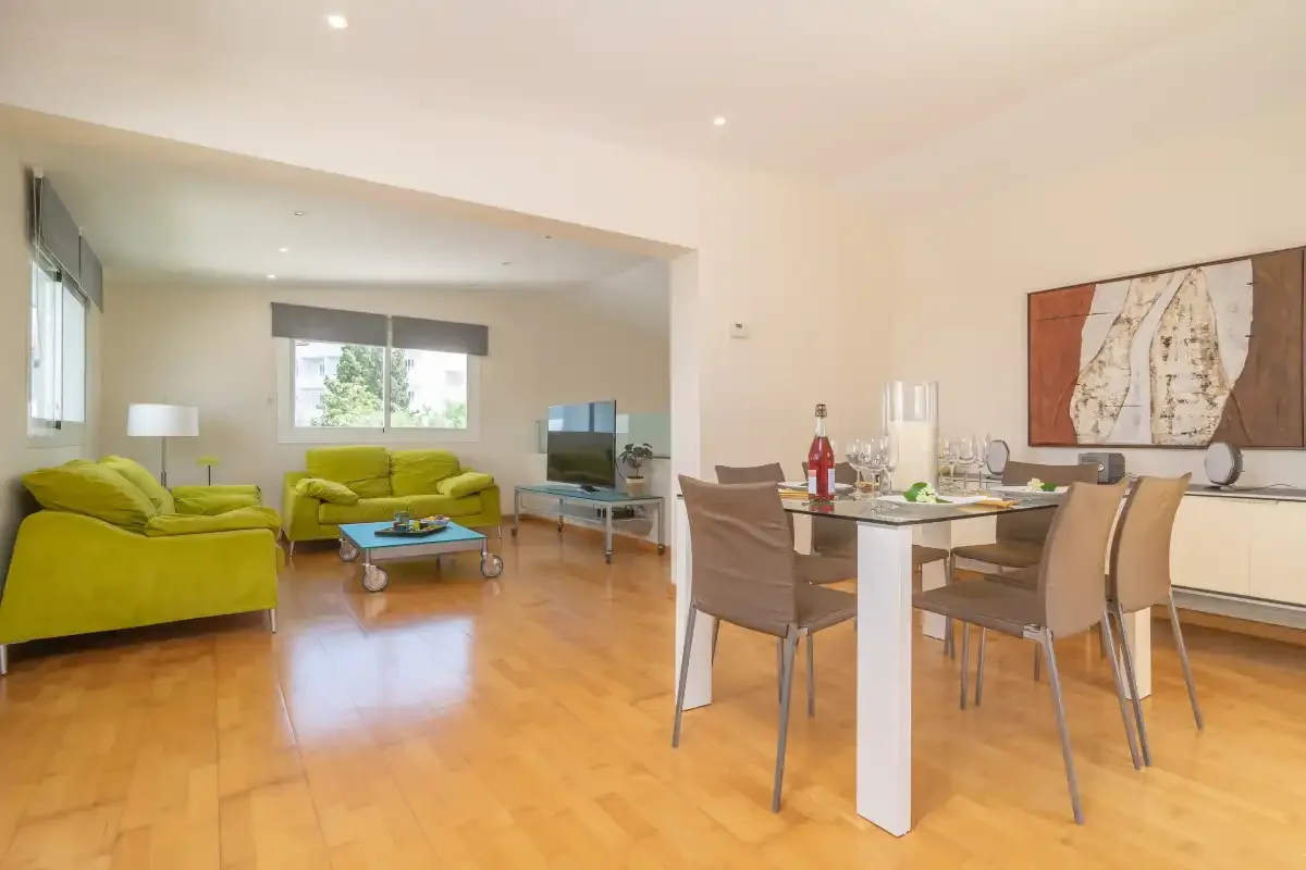 Sala de estar y comedor abiertos, con asientos verdes y una mesa de comedor.
