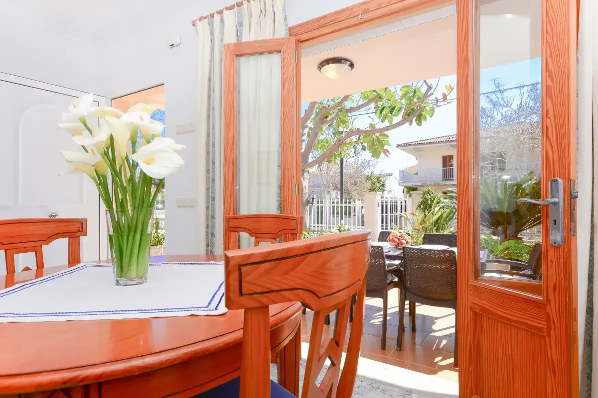 Un comedor se abre a un patio exterior a través de puertas acristaladas con marco de madera.