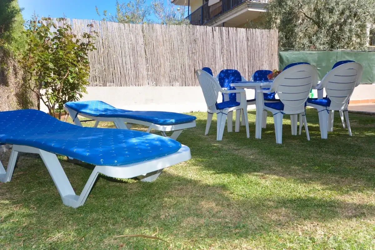 Zona de estar al aire libre con tumbonas azules y una mesa blanca.