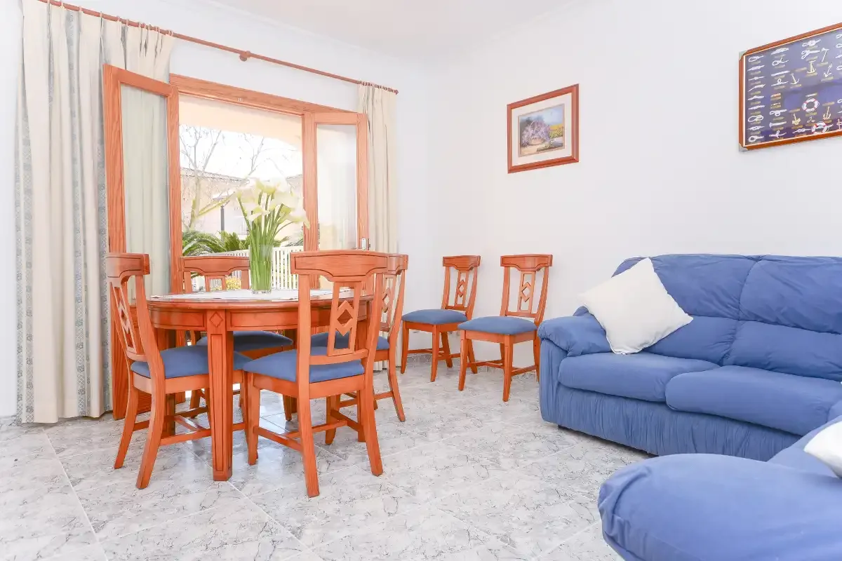 Una zona de estar y comedor con una mesa de madera y asientos azules.