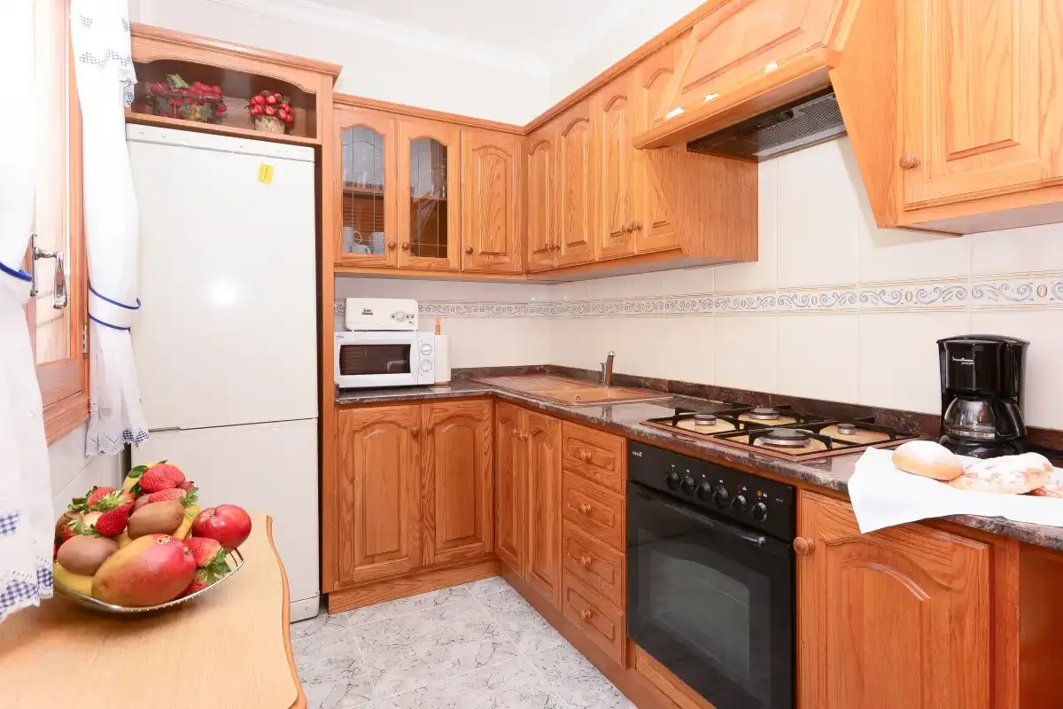 Una cocina con armarios de madera y una estufa sobre la encimera.