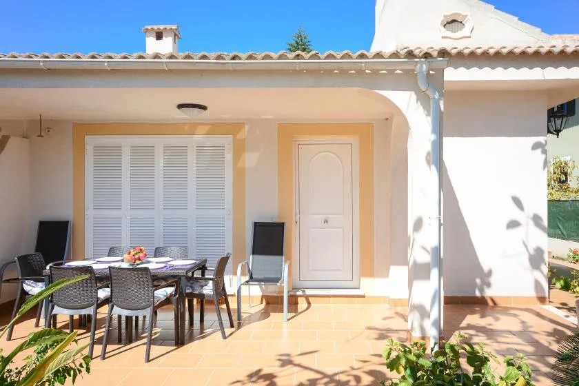 Un patio soleado con asientos al aire libre junto a la entrada de una casa.
