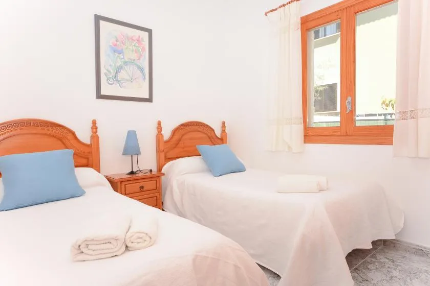 Un dormitorio con dos camas, almohadas azules y una ventana.