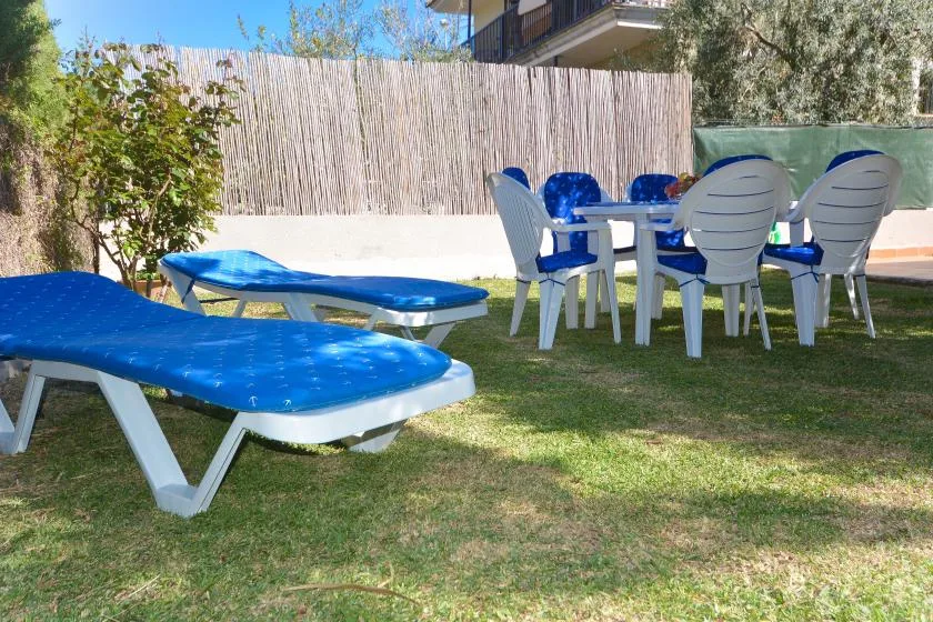 Una zona de estar al aire libre con tumbonas azules y una mesa sobre el césped.