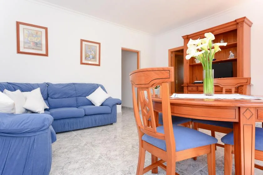 Una zona de estar y comedor con asientos azules y una mesa de madera.
